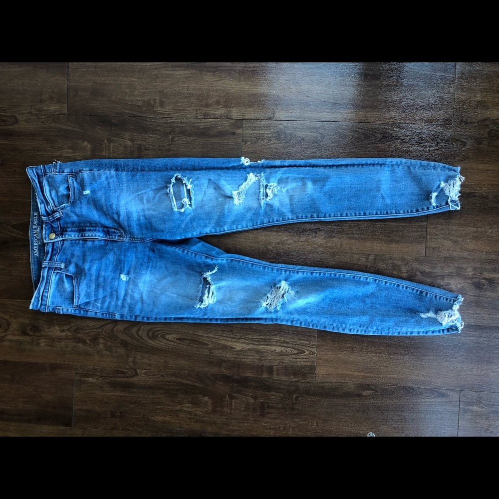 Medium wash destroyed denim jeans with rip hem